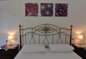 a bed with two white pillows and three paintings on the wall at Haus Katerina in Vourvourou