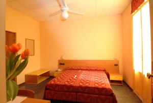 a bedroom with a bed with a red bedspread at Hotel San Geminiano in Modena