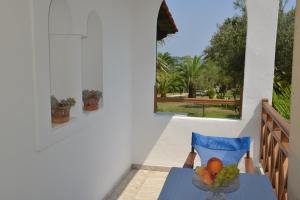 a table with a bowl of fruit on a balcony at Haus Katerina in Vourvourou