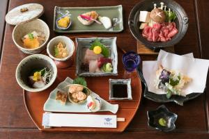 une table avec plusieurs assiettes de nourriture dans l'établissement Sumiyoshi Ryokan, à Takayama