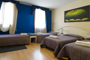 2 camas en una habitación con paredes y ventanas azules en Hotel La Terrazza, en Vicenza