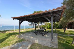a picnic table under a wooden pavilion next to the ocean at Haus Katerina in Vourvourou