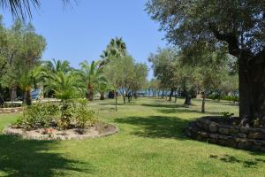 a park with trees and grass and a stone wall at Haus Katerina in Vourvourou