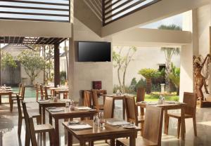 a restaurant with wooden tables and chairs and a flat screen tv at Daluman Villas in Seminyak