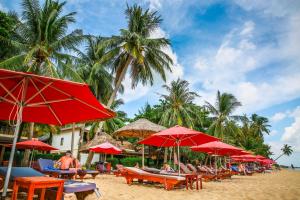 a group of tables and umbrellas on a beach at Tropicana Resort Phu Quoc in Phú Quốc
