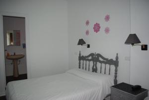 1 dormitorio con 1 cama con sábanas blancas y adornos en la pared en Hotel Lanjaron en Lanjarón