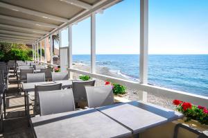 Eine Reihe von Tischen und Stühlen auf einem Balkon mit Meerblick in der Unterkunft Torremare in Marine du Miomo