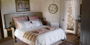um quarto com uma cama grande com almofadas cor-de-rosa e brancas em Athanor Cottages em Hogsback