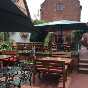 a patio with tables and chairs and an umbrella at The Talbot Inn in Much Wenlock
