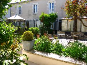 a garden with plants and chairs and an umbrella at La Maison Douce in Saint-Martin-de-Ré