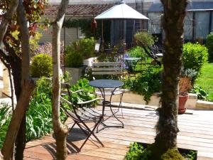a patio with a table and chairs in a garden at La Maison Douce in Saint-Martin-de-Ré