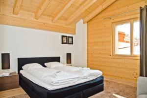 a large bed in a room with a wooden ceiling at Apartment Silbersee - GRIWA RENT AG in Grindelwald