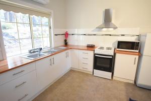 a kitchen with white cabinets and a sink and a microwave at Emu Lodge Country Retreat in Lal Lal