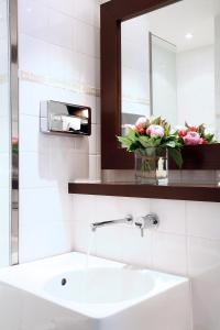 La salle de bains est pourvue d'un lavabo, d'un miroir et de fleurs. dans l'établissement Le Clos Medicis, à Paris