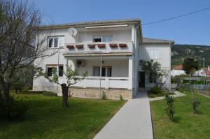a white house with a sidewalk in front of it at Apartments Antonio in Baška