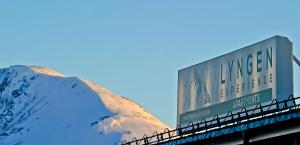a sign on top of a bridge with a mountain at Lyngen Experience Apartments in Nord-Lenangen