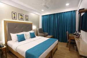 a bedroom with a large bed and a blue curtain at Citizen Hotel in Mumbai