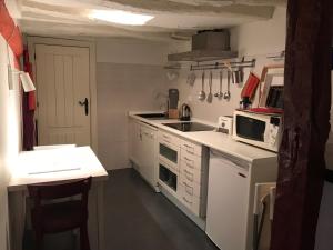una pequeña cocina blanca con fregadero y microondas en Apartamento loft la casa de las Pajaritas en Pasarón