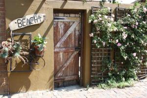 een oude houten deur aan de zijkant van een gebouw met bloemen bij The Yardt Guest House in Trichardt