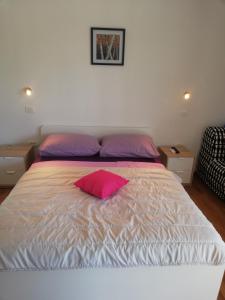 ein Schlafzimmer mit einem Bett mit einem rosa Kissen darauf in der Unterkunft Apartmani Sladic in Skradin