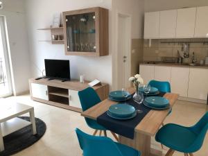 een keuken en eetkamer met een tafel en blauwe stoelen bij Apartman Vodice in Vodice