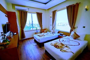una camera d'albergo con due letti e una grande finestra di The Hotel Nova a Mandalay