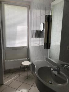 a bathroom with a sink and a stool next to a window at Akzent Hotel-Restaurant Albert in Dorsten