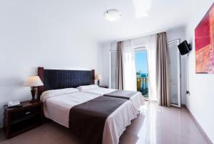 a bedroom with a large bed and a balcony at Toboso Apar - Turis in Nerja