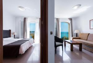 a bedroom with a bed and a living room with a couch at Toboso Apar - Turis in Nerja