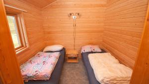 a room with two beds in a wooden cabin at Hytte Camp Nordkapp - Blue in Skarsvåg
