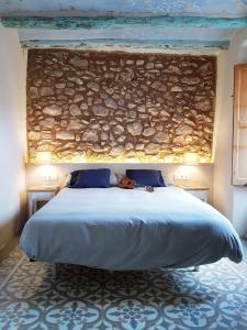 1 dormitorio con 1 cama grande y pared de piedra en Can Jaume Porxo, en Pratdip