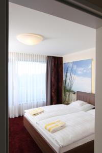 a bedroom with a large bed with two towels on it at Hotel Seelust in Cuxhaven