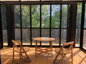 einen Tisch und Stühle in einem Zimmer mit Fenstern in der Unterkunft Minpaku Momotaro Bekkan in Kasugai