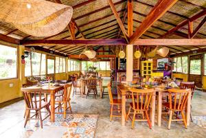 uma sala de jantar com mesas e cadeiras de madeira em Banana Bamboo Ecolodge em Ubatuba