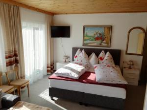 a bedroom with a bed with red and white pillows at Pension Brunner in Bad Kleinkirchheim