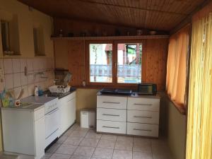 eine Küche mit weißen Schränken und einem Fenster in der Unterkunft Eszter Vendeghaz in Berekfürdő