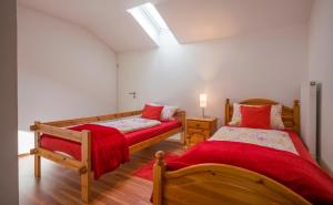 a bedroom with two beds with red sheets at Heidinger in Oberaudorf