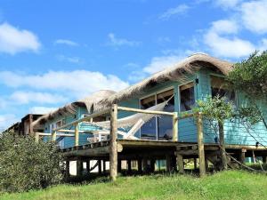 a large house with a thatched roof at Cabaña PRAIA in Punta Del Diablo