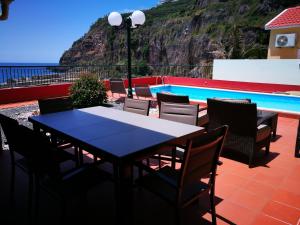 a table and chairs on a patio next to a swimming pool at Casa Maresia in Ponta do Sol