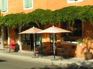 two tables and chairs with umbrellas on a sidewalk at Hotel Des Sites in Salavas