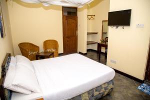a bedroom with a bed and a flat screen tv at Daisy Comfort Home in Dar es Salaam
