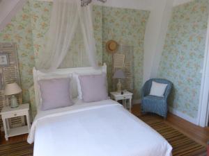 a bedroom with a white bed and a blue chair at La Liniere in Honfleur