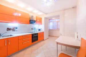 トムスクにあるКвартиры на Мираのキッチン(オレンジ色のキャビネット、テーブル付)