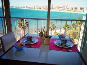 エル・カンページョにあるApartamento Cabo Azul Playa Campelloのビーチ沿いのバルコニーにテーブルと食器