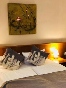 a bedroom with a bed with two pillows and a painting at Hotel Condor in Hamburg