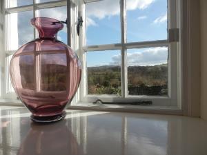 un jarrón de cristal sentado en una mesa frente a una ventana en Wheelgate, en Torver