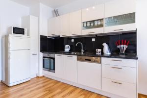 a kitchen with white cabinets and black counter tops at Apartman Orlando in Korčula