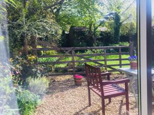 eine Holzbank in einem Garten mit einem Zaun in der Unterkunft Cherrybrook in Glastonbury