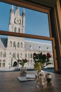 a table with flowers in front of a large building at Hotel New Regina in Ypres