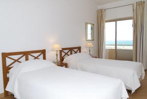 two beds in a room with a view of the ocean at Apartamentos Turisticos Vila Palmeira in Lagos